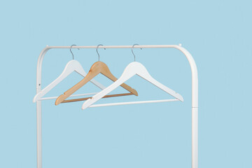 Rack with wooden clothes hangers on blue background