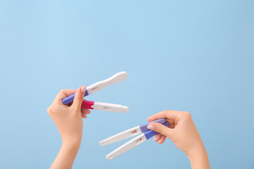 Female hands with different pregnancy tests on color background