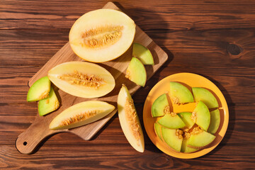 Board and plate with pieces of sweet melon on wooden table