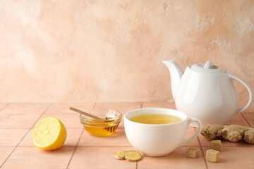 Cup of ginger tea and bowl with honey on pink tile table