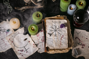Witch's magic attributes with spell book on dark table