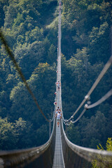 Obraz premium People while crossing the Tibetan bridge of Dossena.Which is the longest in the world