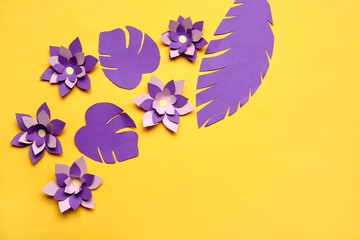 Colorful origami flowers and leaves on yellow background