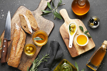 Bowls and bottles of fresh olive oil with bread on black background