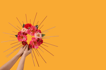 Female hands holding flower crown on yellow background