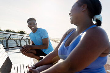 Smiling african american man and body positive woman in sportswear exercising together outdoors