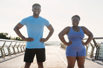 African American man and woman in sportswear after training outdoors, standing, looking at camera