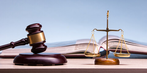 Legal Law and Justice concept - Open law book with a wooden judges gavel on table in a courtroom or...