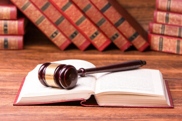 Legal Law and Justice concept - Open law book with a wooden judges gavel on table in a courtroom or law enforcement office. Copy space for text.