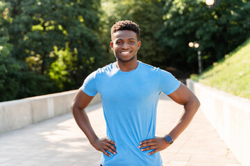 Attractive African man in blue t shirt posing for picture, looking at camera, healthy lifestyle