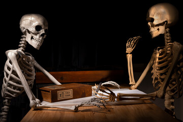 Two Halloween skeletons doing their taxes at a table