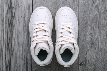 White sneakers lie on gray floor. View from above.