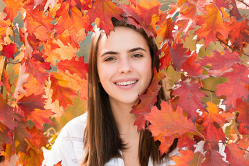 Naklejka na ściany i meble Portrait of young woman with autumn leafs. Romantic girl dream, hold fall maple leaves. Autumnal season.
