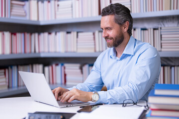 Obraz premium Portrait of teacher with book in library classroom. Handsome teacher in university. Teachers Day. Good school teacher. Tutor at college. Man with books in library. Knowledge and education concept.