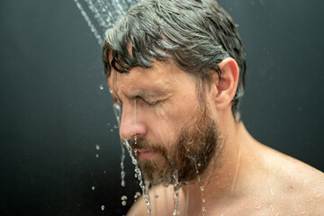 Millennial man washing hair in bath. Guy bathing shower head in bathtub. Face in foam in shower....