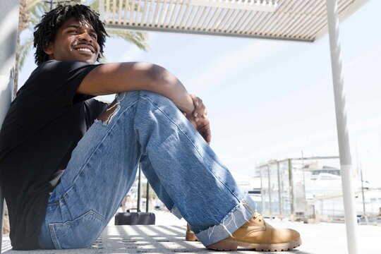 Afro boy with dark skin and curly hair sitting in a bank smiling