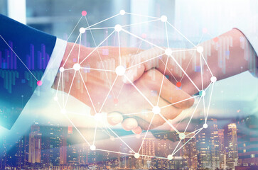 Deal or partnership concept. Multiple exposure with cityscape, charts and photo of businesspeople shaking hands