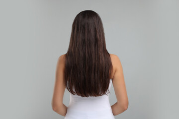 Obraz premium Woman with damaged messy hair on grey background, back view