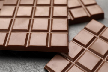 Delicious milk chocolate bars on black table, closeup