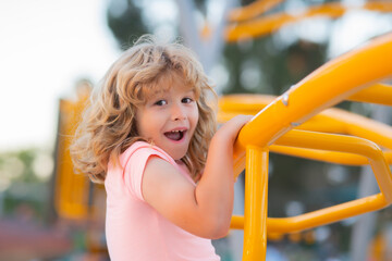 Summer, childhood, leisure and children concept. Happy little boy climbing on children playground.
