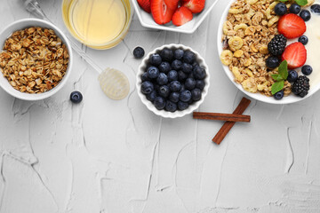 Tasty oatmeal, honey and fresh berries served on white textured table, flat lay with space for text. Healthy breakfast