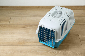Light blue pet carrier on floor indoors. Space for text