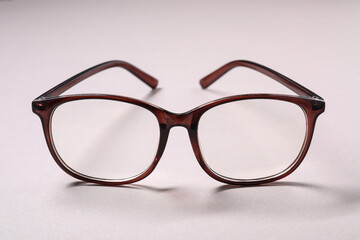 Stylish pair of glasses on light background, closeup