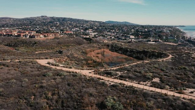 4K drone aerial tracking and stablishing shot of a beach with a pier in California