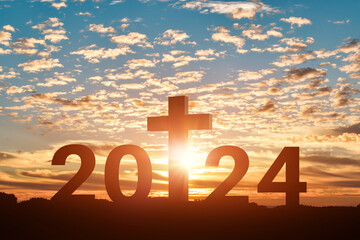 Silhouette of Christian cross with 2024 years at sunset background. Concept of Christians new year...