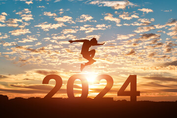 Silhouette of man jumping to Happy new year 2024 in sunset or sunrise background.