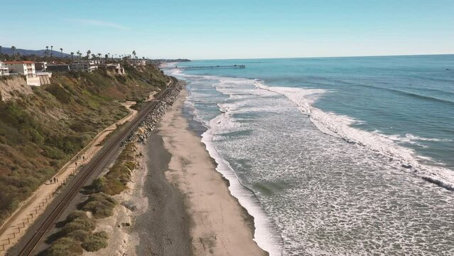 4K drone aerial tracking and stablishing shot of a beach with a pier in California