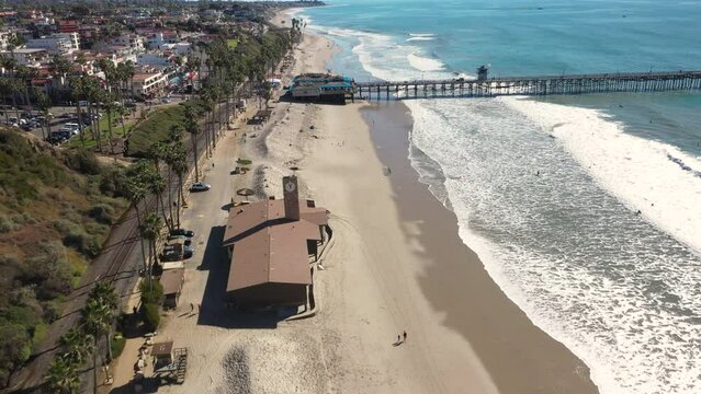 4K drone aerial tracking and stablishing shot of a beach with a pier in California