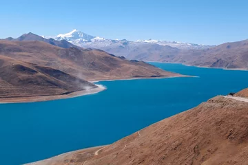 Foto op Canvas Lake Yamdrok Tso in Tibet is a revered azure gem, symbolizing wisdom and compassion. Embraced by serene majesty, it's surrounded by snow-capped peaks. © Tenzin & Li