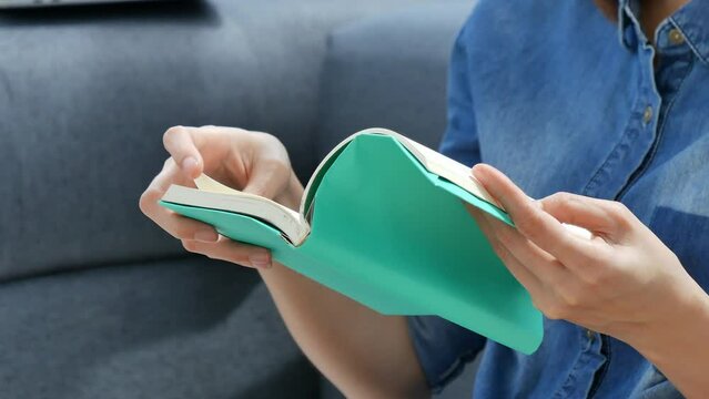 Young asian woman reading book on cozy couch sofa at warm home. Relax woman holding book read on sofa near window happiness.woman reading open book leisure mind. Happiness woman lifestyle at home
