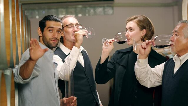 Group of Man and woman sommelier tasting red wine in wooden barrel at vintage wine cellar in wine factory. Winery, wine shop, brewery liquor manufacturing industry and winemaker business concept.