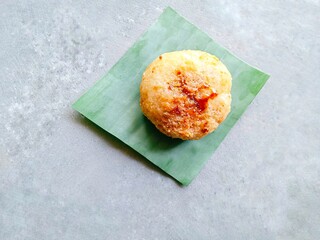 Homemade traditional snack called ondol-ondol or grated cassava filled with brown sugar and then fried on gray background