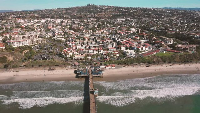 4K drone aerial tracking and stablishing shot of a beach with a pier in California