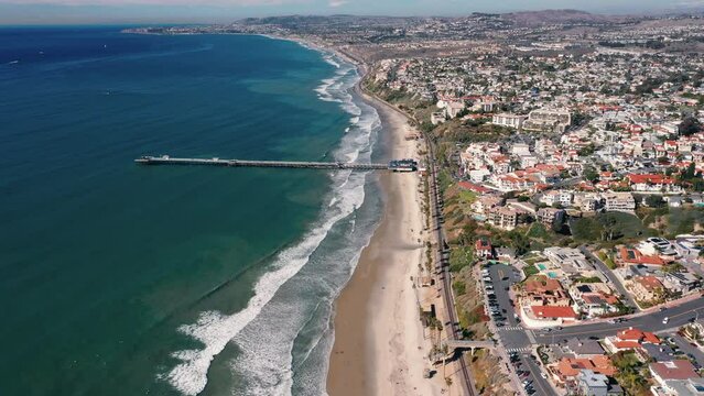 4K drone aerial tracking and stablishing shot of a beach with a pier in California