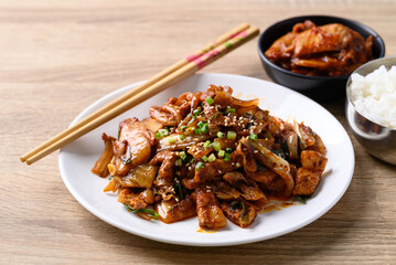 Korean stir fried kimchi cabbage with pork eating with kimchi and cooked rice on wooden table