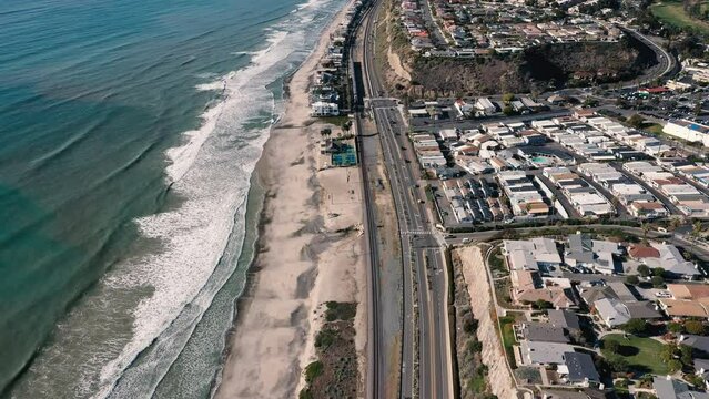 4K drone aerial tracking and stablishing shot of a beach with a pier in California