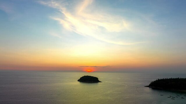 .Aerial hyperlapse scenery yellow sunset in beautiful sky above Pu island in sunset. .yellow sunset behind Pu island at Kata beach Phuket Thailand.4k stock footage video in travel concept.Sky texture.