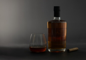 Glass and bottle of whiskey and cigar on black background