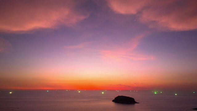 .Aerial hyperlapse The lights from the fishing boat shine beautifully in the sea at dusk..This stunning view captures the beauty of the island as the setting sun casts a pink hue across the sky..