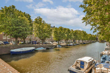 some boats docked in the water near trees and buildings on either side of the river with blue skies above them