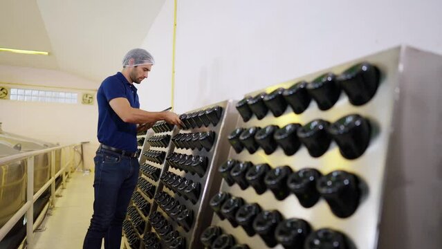 Caucasian man winemaker staff inspecting wine sediment in the bottle in modern wine factory. Winery manufacturing quality control. Winery manufacturing industry and winemaking concept.