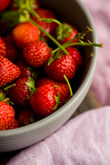 Red ripe strawberry in gray bowl on the rustic background. Selective focus. Shallow depth of field.