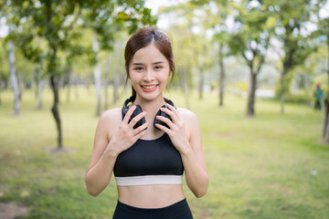 Asian beautiful and sportive woman wearing headphone while exercising in the garden at morning time. Healthy Concept.