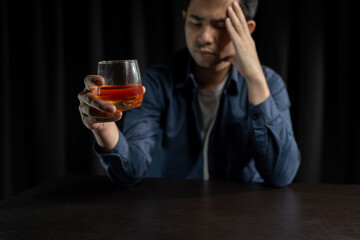 Asian businessman stressed at work failed business problem paperwork Desperate man holding a glass of alcohol Sitting at the desk late at night in the office Depressed and hopeless concept.