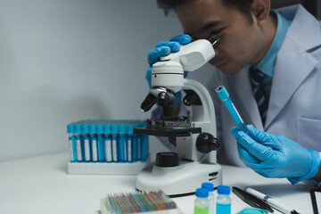 Asian scientist looking at a microscopic sample of experimental cyan is doing an in vitro vaccine...