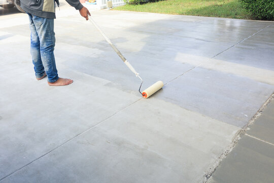 Worker and renovation work. To using roller painting mortar cement or finishing material for repair crack, skim coat or improvement surface of concrete pavement floor or slab for driveway or garage.